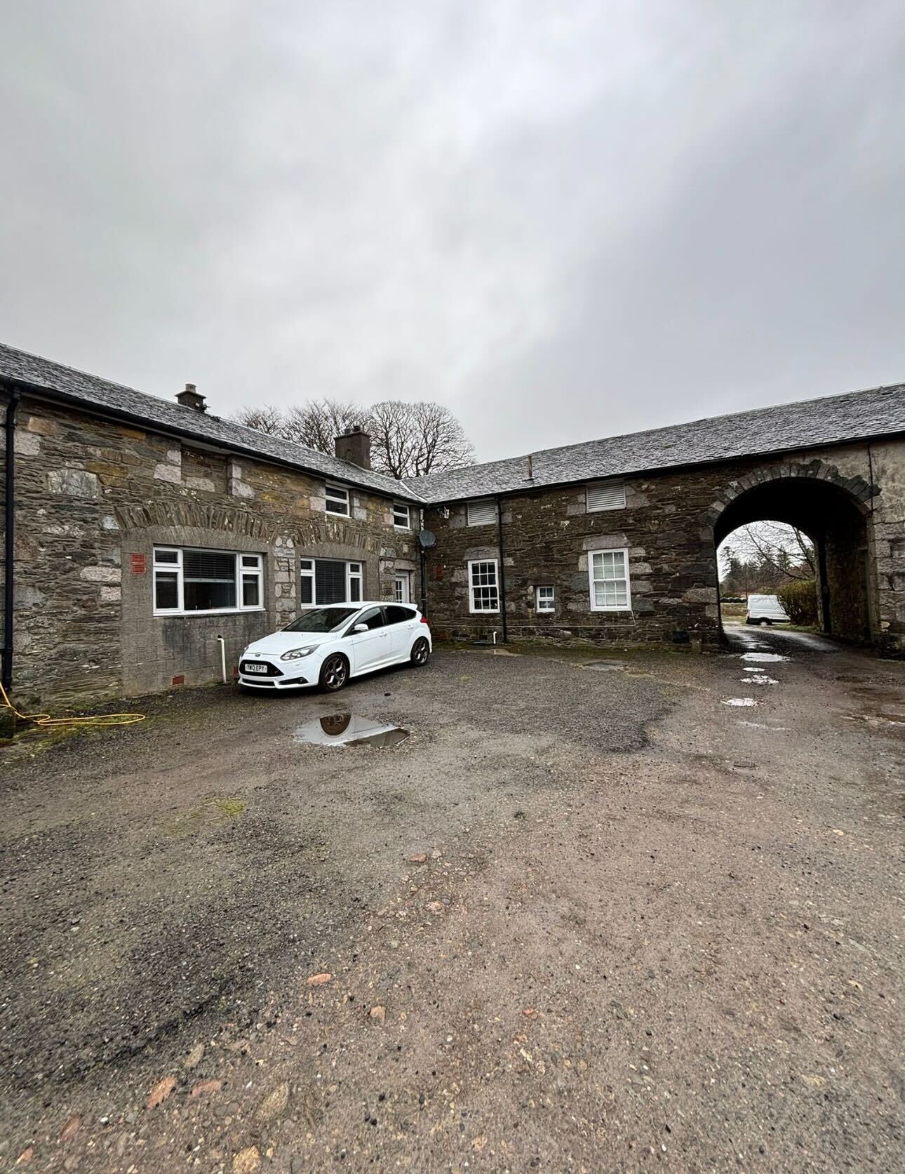 Scottish heritage farm steading exterior - traditional granite stonework, slate roof and arched carriage entrance before renovation