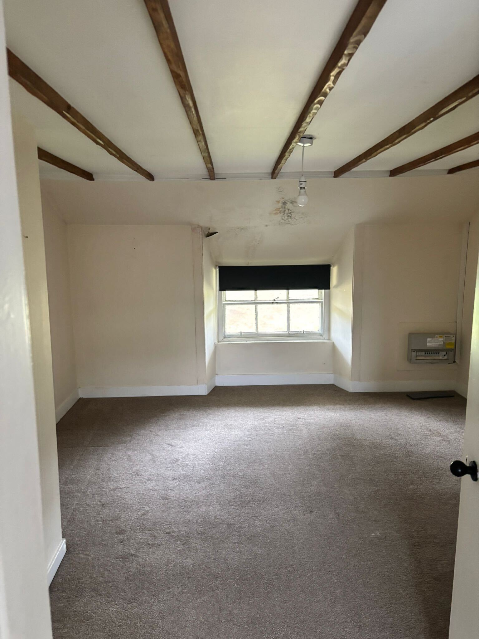 Scottish heritage renovation interior - exposed original timber roof beams and period sash window showing existing condition before works